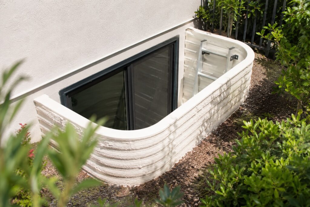 Below grade egress window well with ladder built into a Santa Barbara hillside foundation